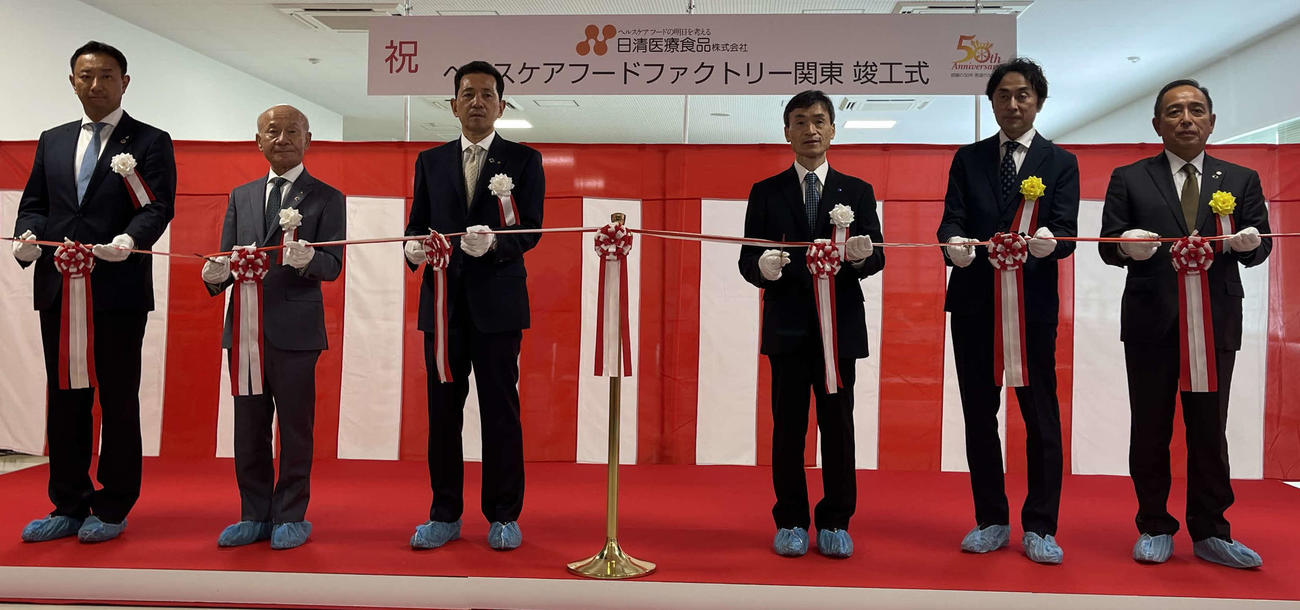 テープカットに臨んだ左から松田工場長、菅井副会長、立林社長、ワタキューホールディングス村田社長、三菱ケミカルエンジニアリング清水取締役、古久根建設油井社長
