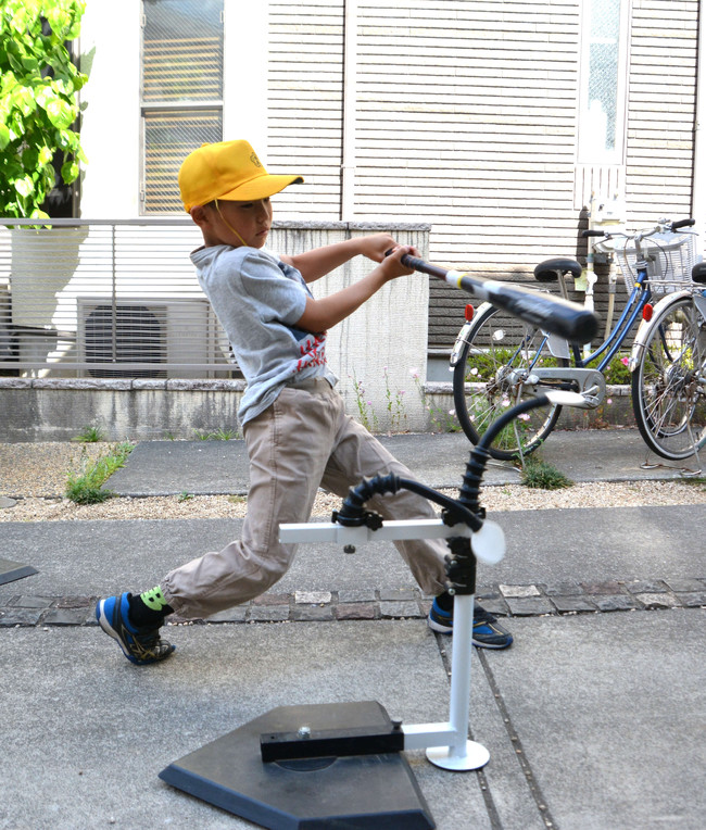 登校前にスウイングパートナーで練習する少年。的を２枚たたくとレベルスイングが体得できる