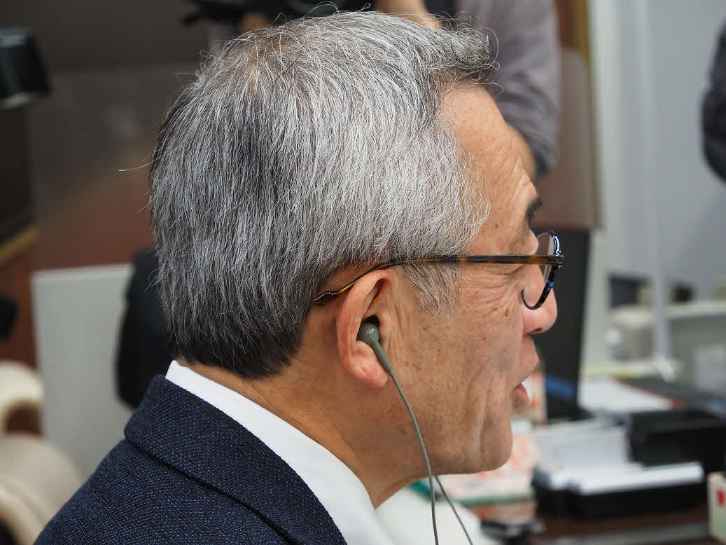 「軟骨伝導イヤホン」を装着して、音の伝わり方を試す顧客