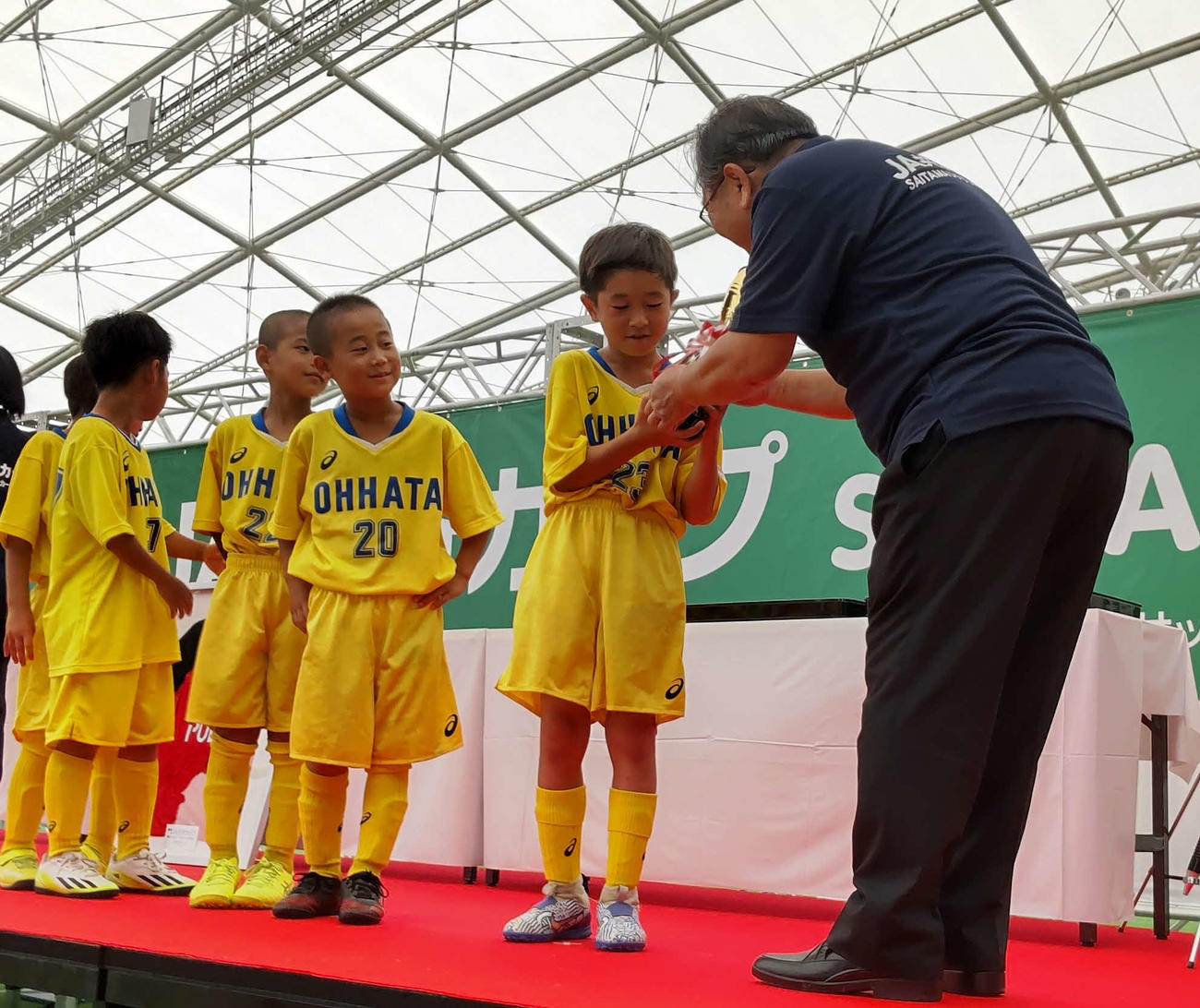 JA共済連埼玉の坂本富雄会長(右)から優勝カップをもらう大幡サッカースポーツ少年団の橋本仁希(はしもとにき)選手