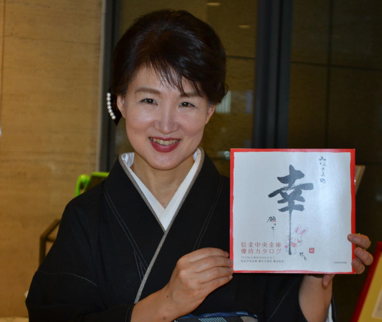 自身が描いた信金中金のカタログを手にする外村さん