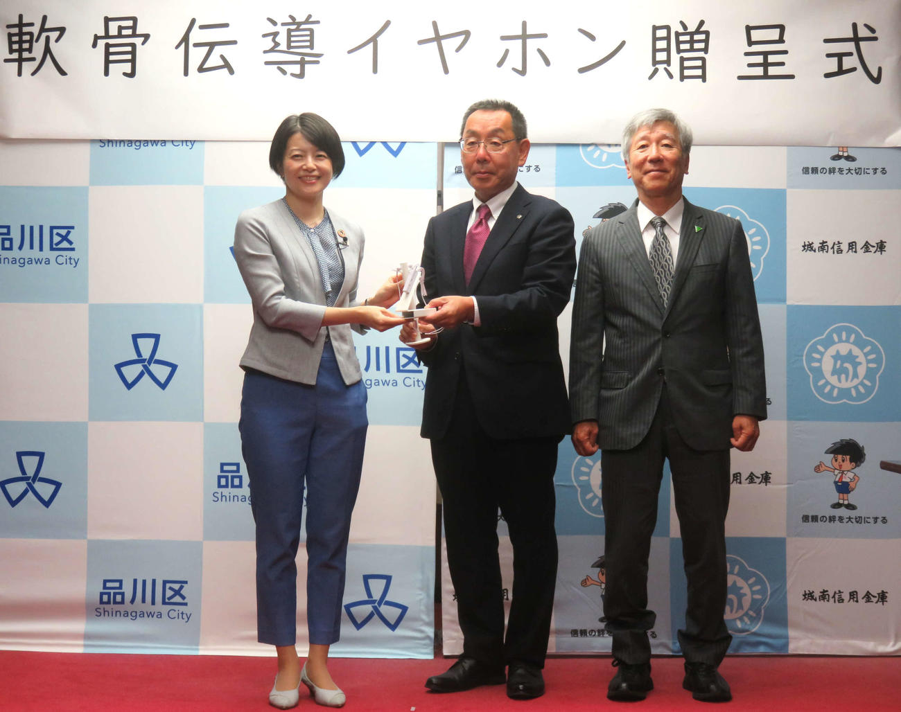 城南信用金庫の林稔理事長（中央）が軟骨伝導イヤホンを森澤恭子・品川区長に贈呈した（右は細井裕司・奈良県立医科大学長）