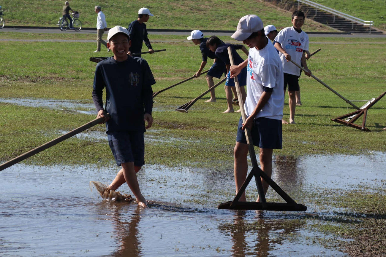 グラウンドの水取り作業も楽しく笑顔で