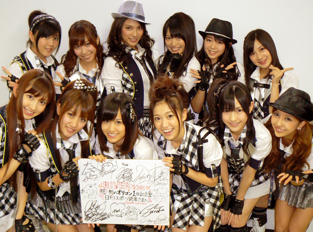 初のチャート1位を記念して、本紙独占でサイン色紙をプレゼントしてくれたAKB48。前列左から小嶋陽菜、高橋みなみ、前田敦子、大島優子、渡辺麻友、板野友美。後列左から宮崎美穂、河西智美、秋本才加、北原里英、峯岸みなみ、小野恵令奈（2009年10月27日撮影）