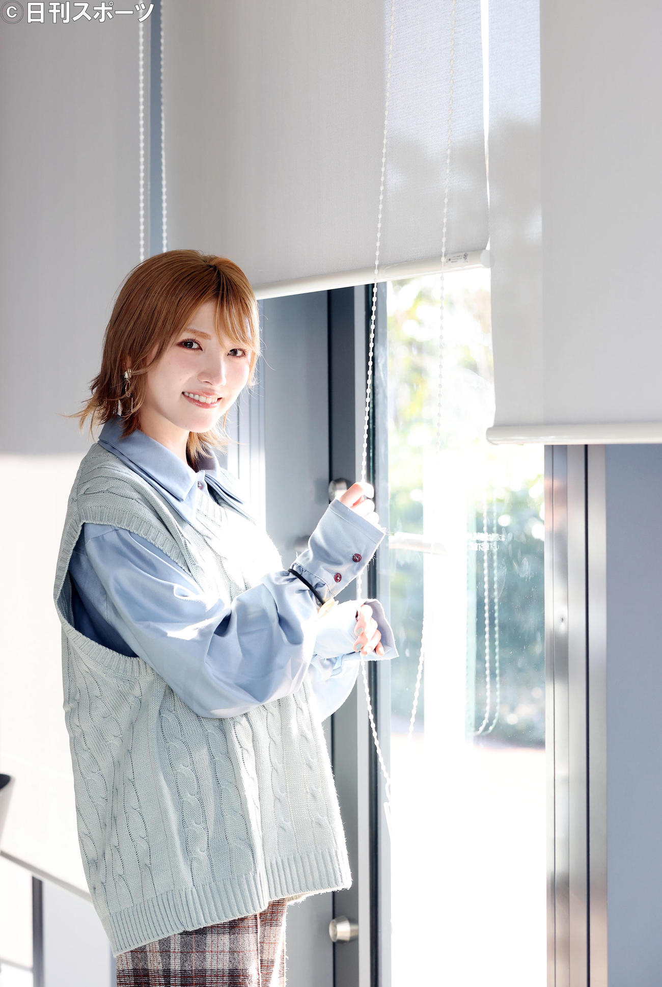 AKB48の岡田奈々は、窓のシェードを上げながら笑顔を見せる（撮影・浅見桂子）
