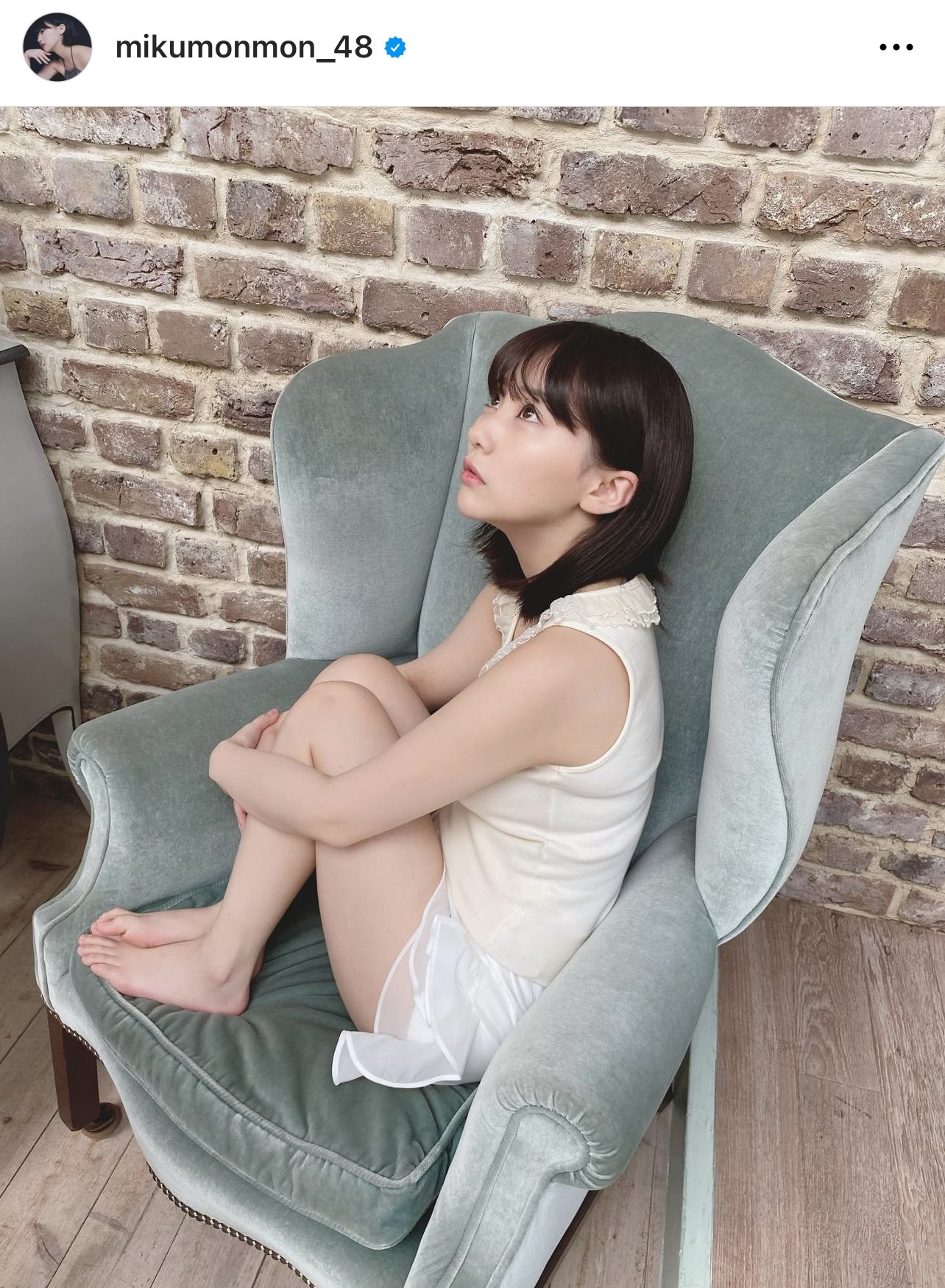白のタンクトップと白の短パン姿でソファーに体育座りするHKT48田中美久（田中美久のインスタグラムから）