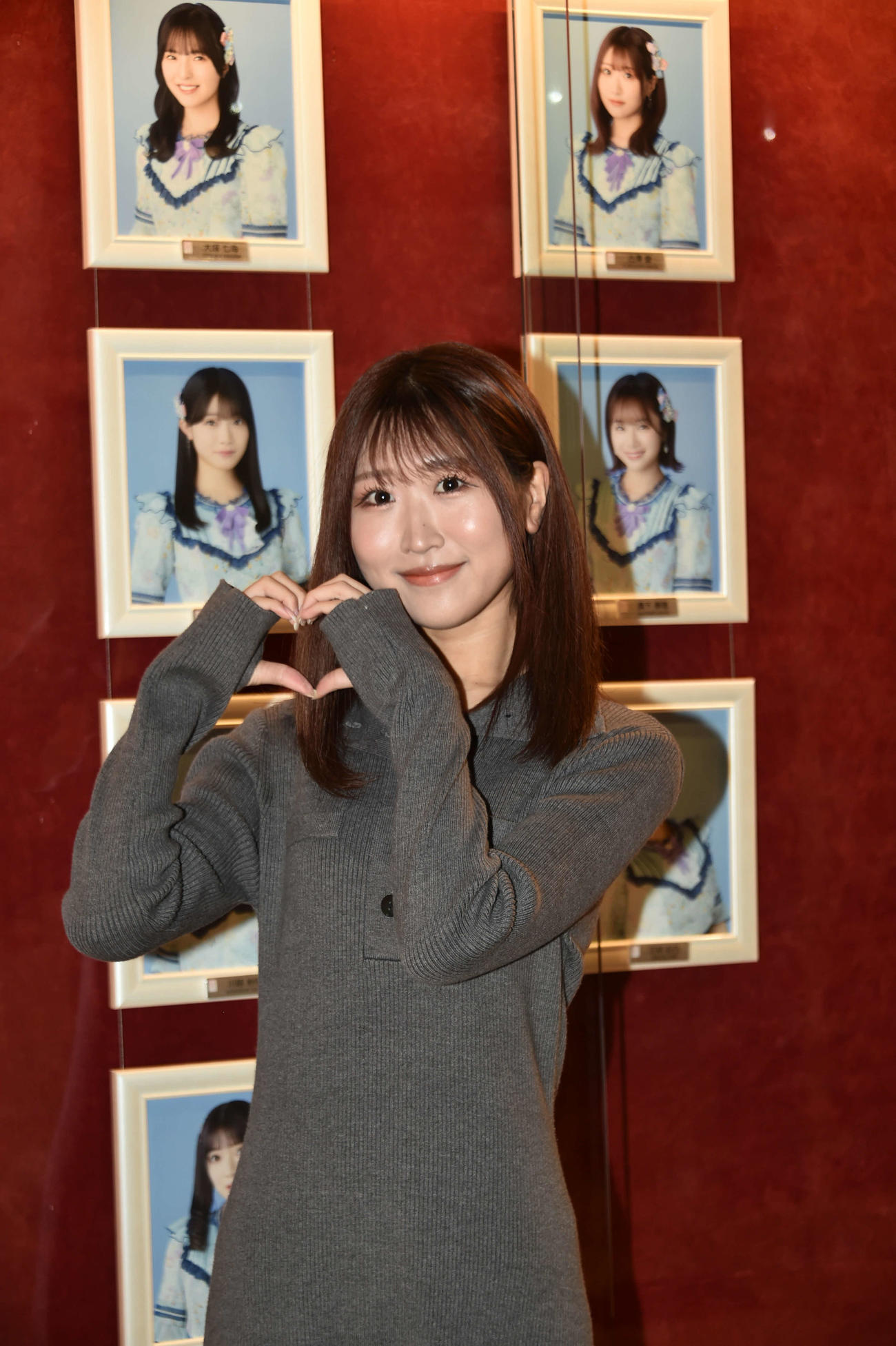 同期の2期生の写真の前で感謝を込めてハートを作る古澤愛
