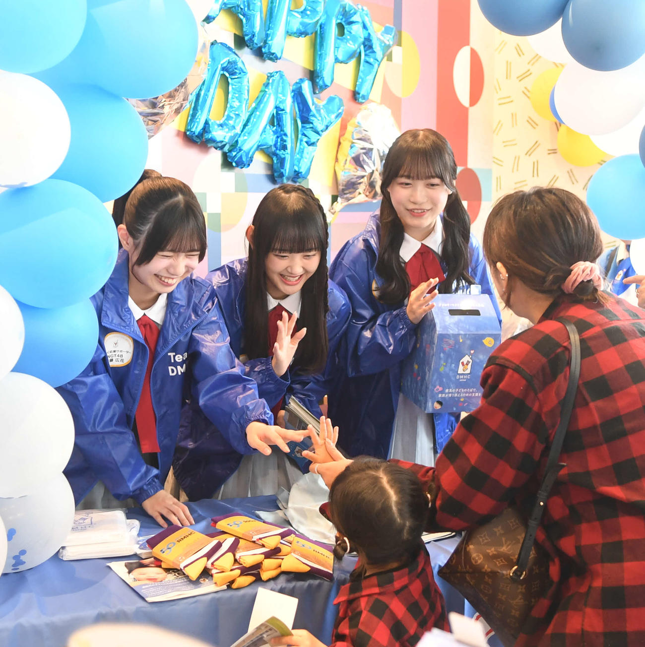 募金した子どもと触れ合い、笑顔のNGT48のメンバー。左から佐藤広花、磯部瑠紅、鈴木凛々花