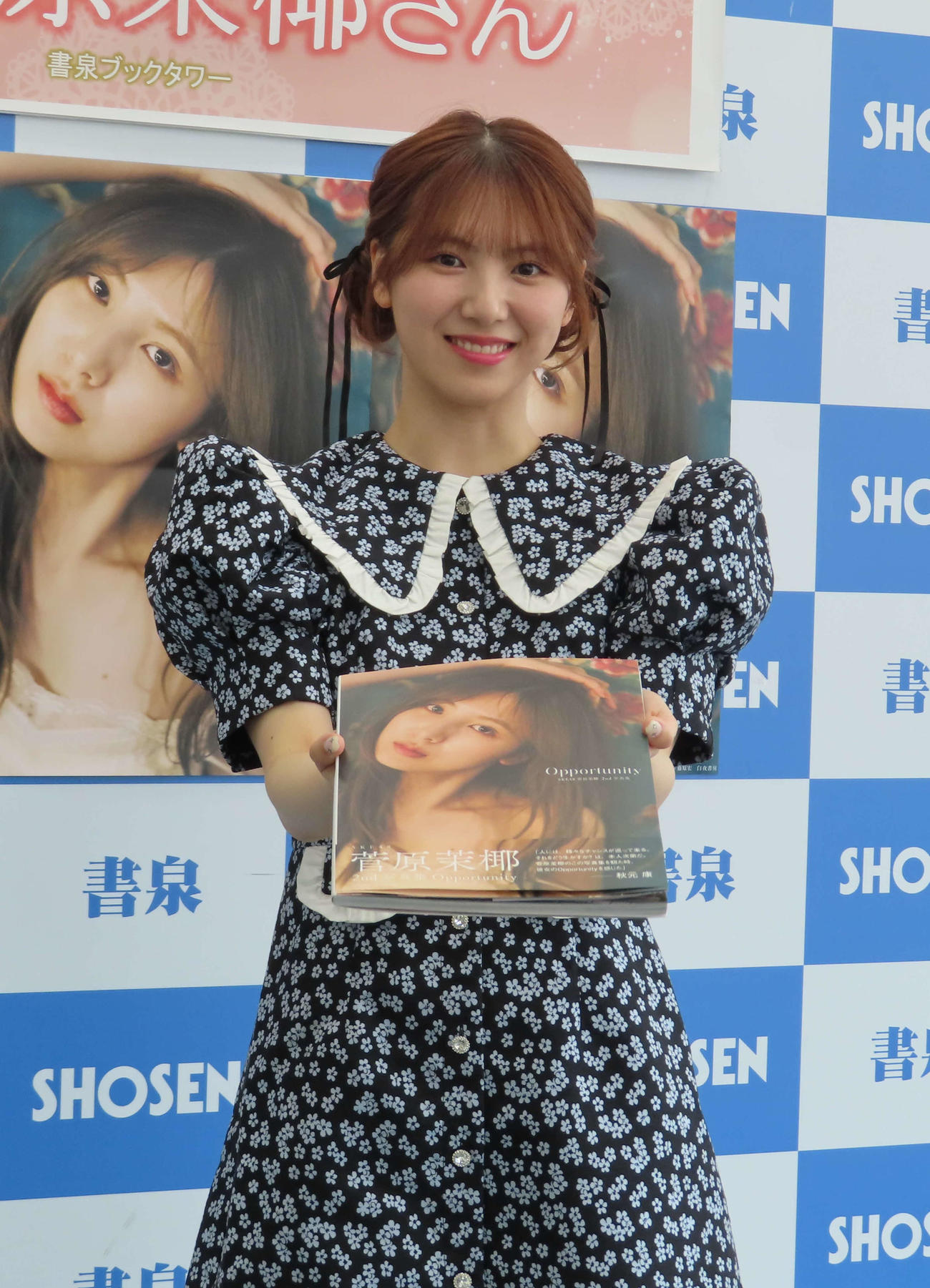セカンド写真集発売記念の会見で、写真集を渡すポーズをする菅原茉椰（撮影・寺本吏輝）