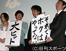 舞台あいさつで、判決の一報風景のように「大ヒット」を掲げる出演者たち