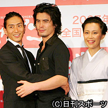 記者会見で抱き合う伊勢谷友介(左)と伊藤英明。右端は木村佳乃