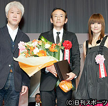 監督賞の周防正行監督（中央）。左はプレゼンターの根岸吉太郎、右は鈴木蘭々