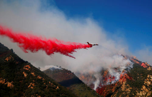 米カリフォルニア州マリブ市で、消火剤を投下する飛行機（ロイター）