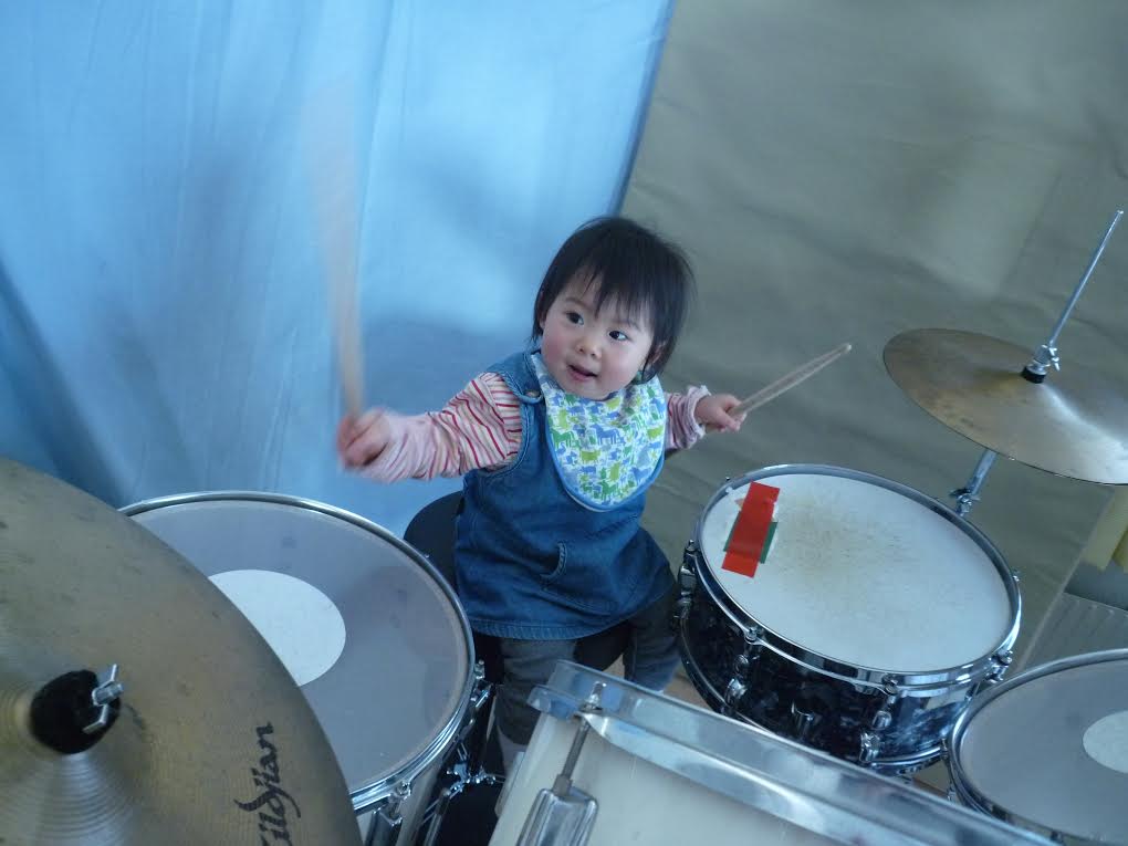 しっかりスティックを握ってドラムセットの前に座る子ども時代のYOYOKA
