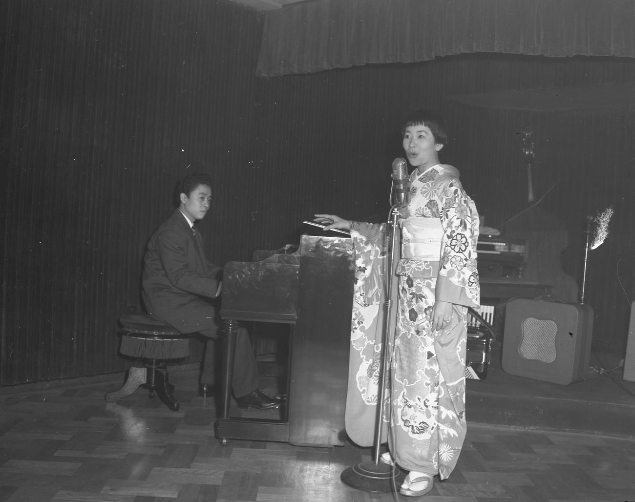 帰国歓迎レセプションで歌うナンシー梅木さん。ピアノ伴奏は中村八大さん（1957年1月撮影）