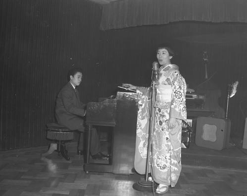 帰国歓迎レセプションで歌うナンシー梅木さん。ピアノ伴奏は中村八大さん（1957年1月撮影）
