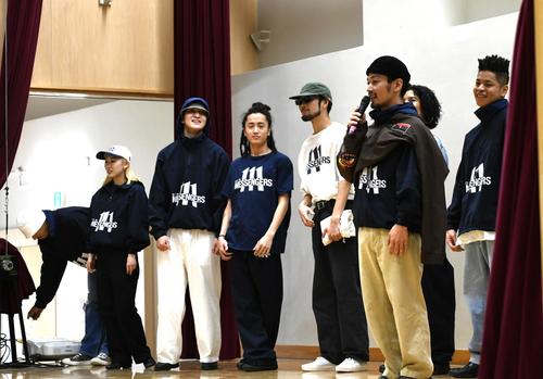 中学校の体育館の舞台上からあいさつするDYM MESSENGERS