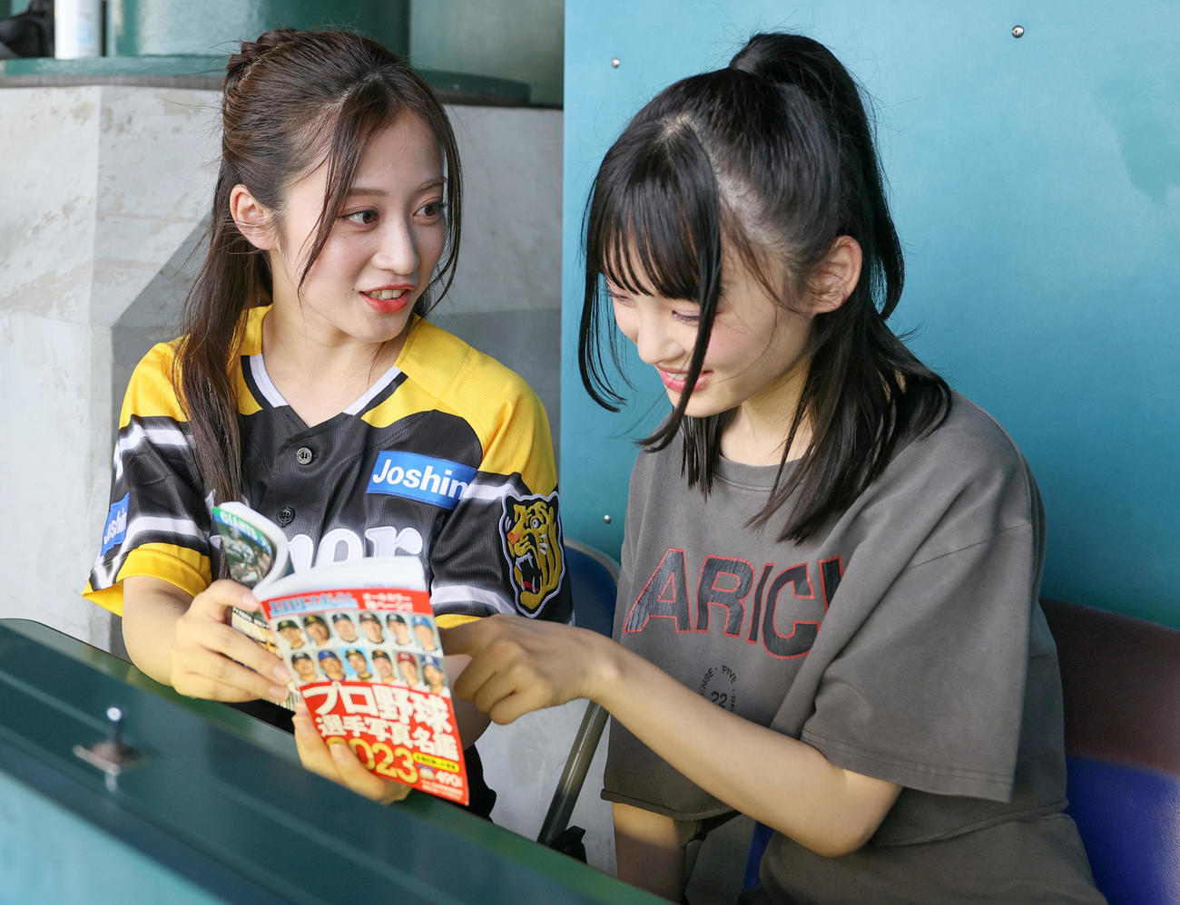 選手名鑑を用いて阪神の選手を教えるNMB48川上千尋（左）と新澤菜央（撮影・上山淳一）