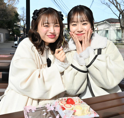 NMB48新澤菜央(左)からサンドイッチを食べさせてもらい笑顔を見せる水田詩織(撮影・石井愛子)