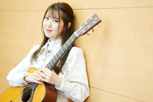 ギターを抱えポーズを決めるおかゆ(撮影・横山健太)