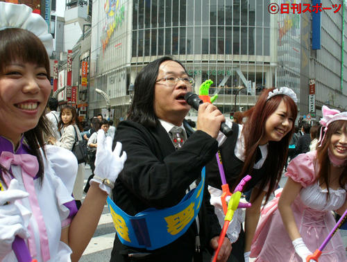 07年4月、東京の渋谷区長選に立候補した宅八郎候補が渋谷駅ハチ公口でマジックハンド片手にメイド姿の女性とともに叫んだ