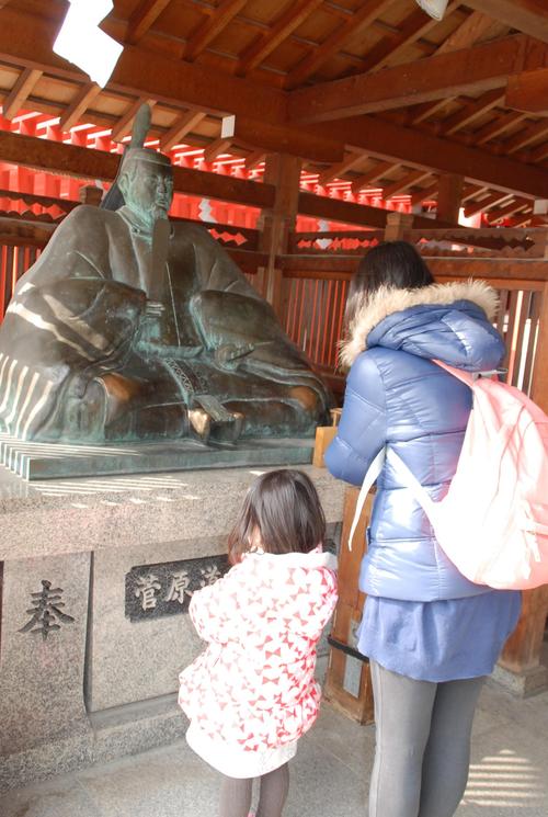 服部天神宮の菅原道真公の銅像に手を合わせる親子（２０１８年２月２４日撮影）