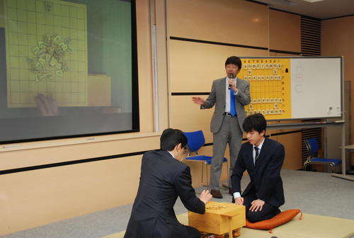 模範対局する谷川浩司九段（手前）と藤井聡太六段、解説をする師匠の杉本昌隆七段（撮影・松浦隆司）