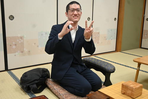 右手で「C」、左手で「2」のポーズを作り、フリークラスから順位戦C級2組への昇級を喜ぶ折田翔吾五段（2023年5月10日撮影）