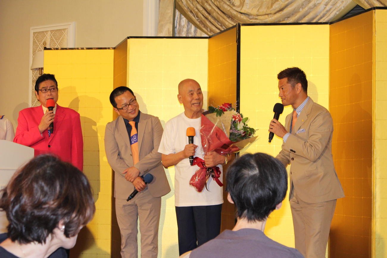 お祝いの花束を受け取った桑原征平。左から中邨雄二ABCアナウンサー、桂吉弥。右端はサッカー元日本代表の播戸竜二