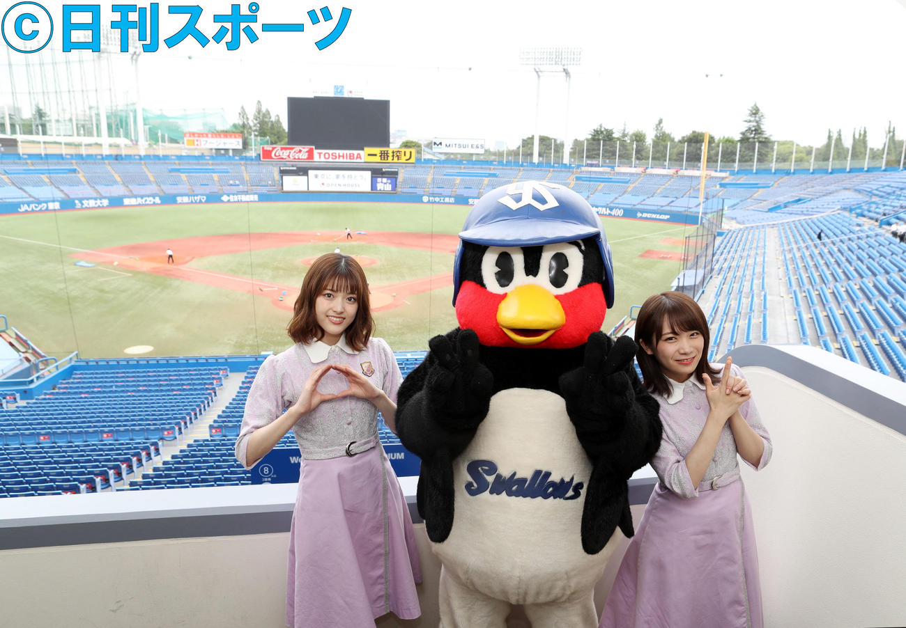神宮球場のグラウンドをバックに、さゆりんごポーズの松村沙友理（左）と、ズッキュンポーズをする秋元真夏（右）。中央はつば九郎（2018年5月撮影）