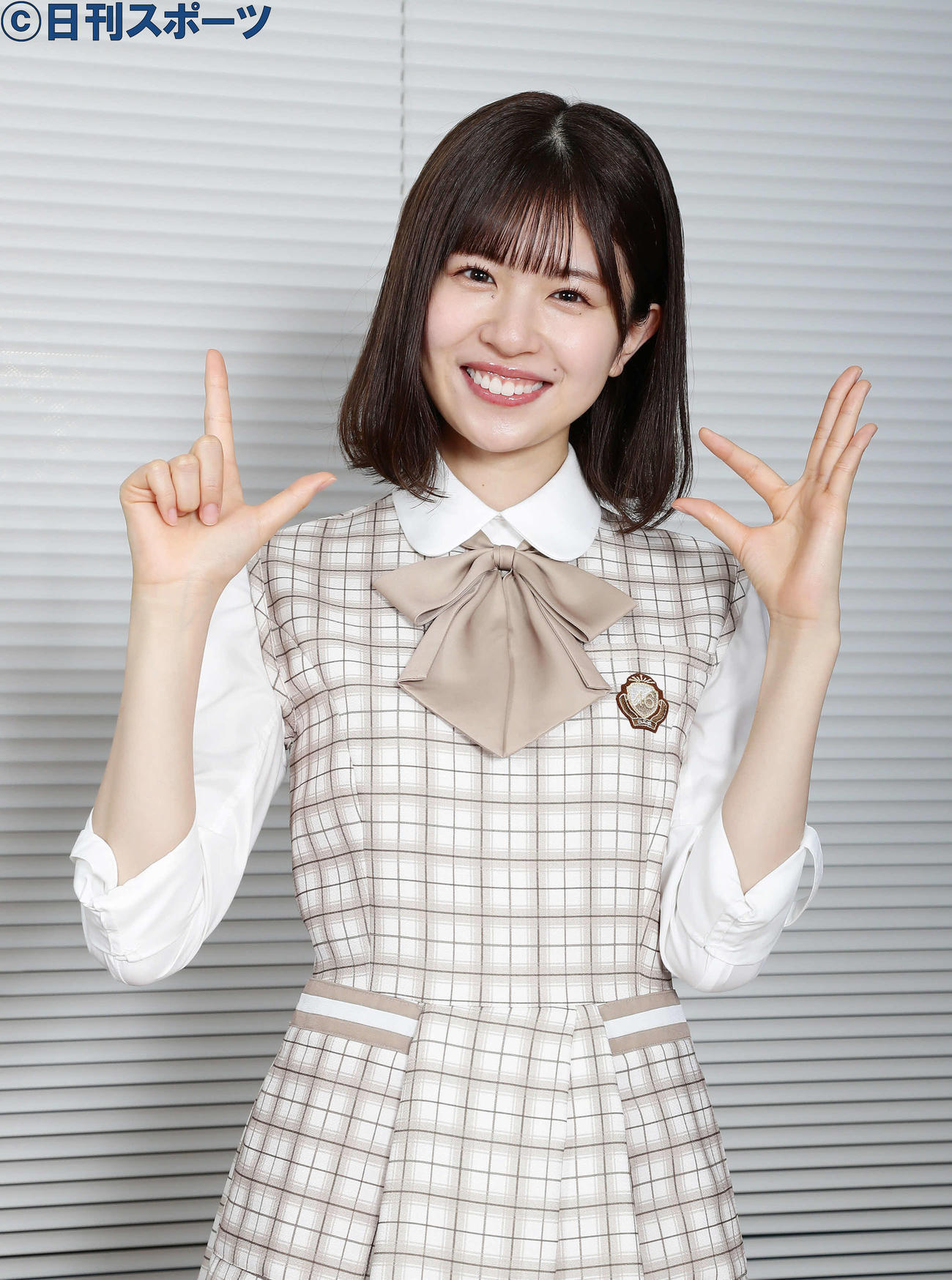 右手でラヴィット！、左手で日向坂のポーズを作って、ほほえむ松田好花（撮影・丹羽敏通）