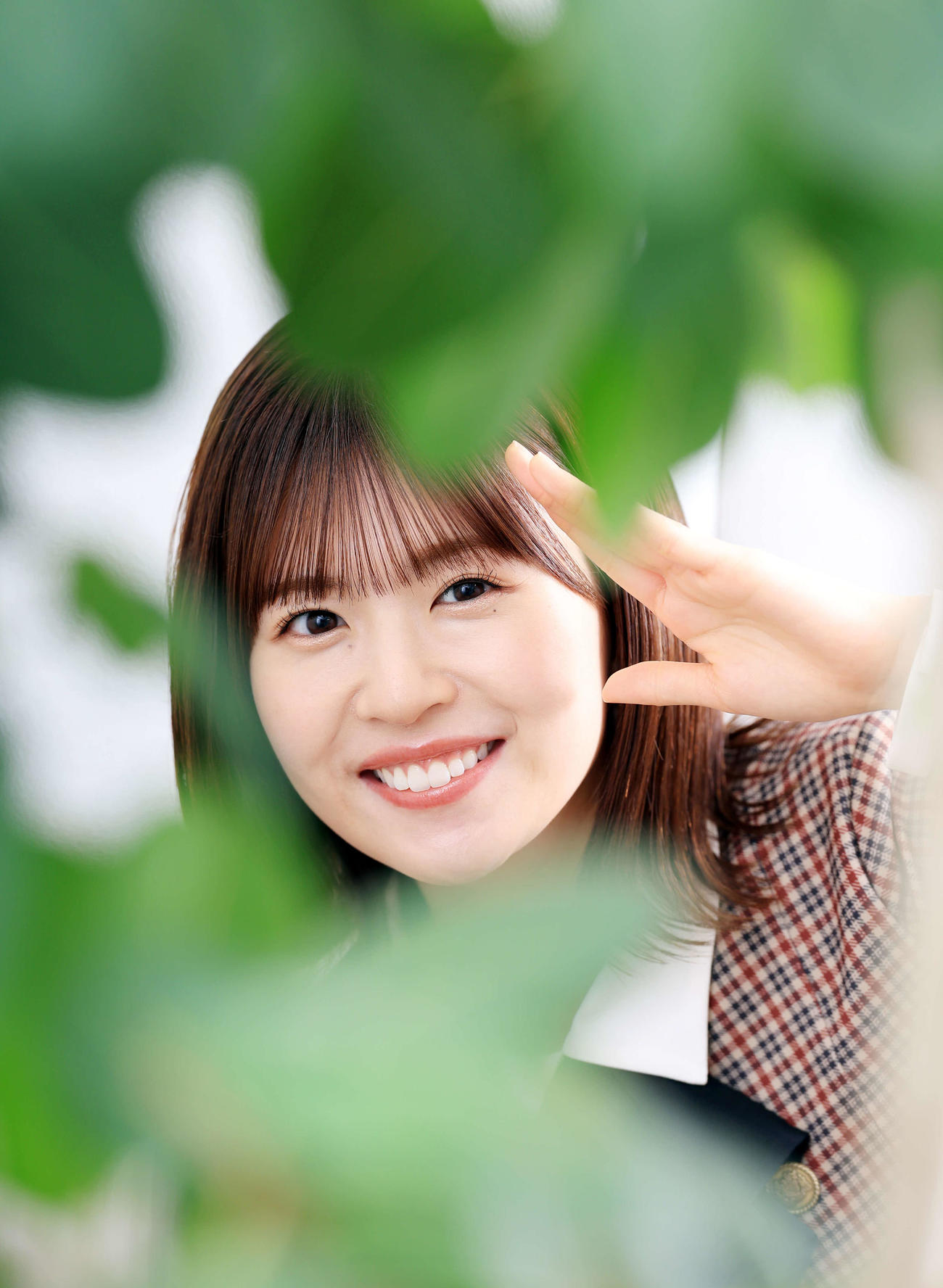 緑が大好きという日向坂46の松田好花は、観葉植物の奥で笑顔を見せる（撮影・浅見桂子）
