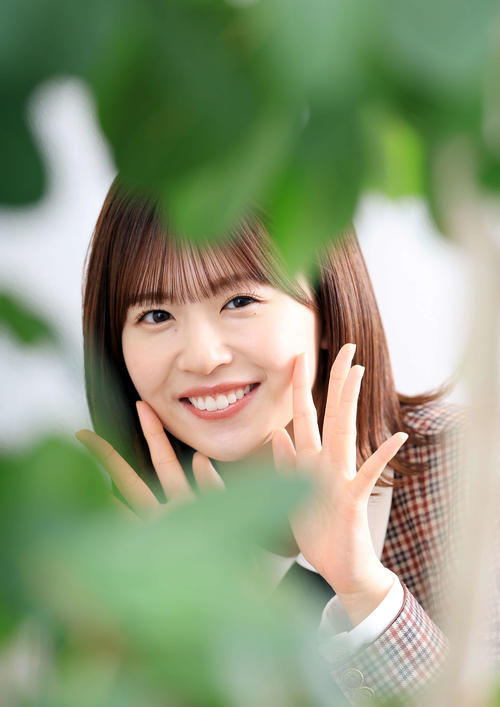 緑が大好きという日向坂46の松田好花は、観葉植物の奥で笑顔を見せる（撮影・浅見桂子）