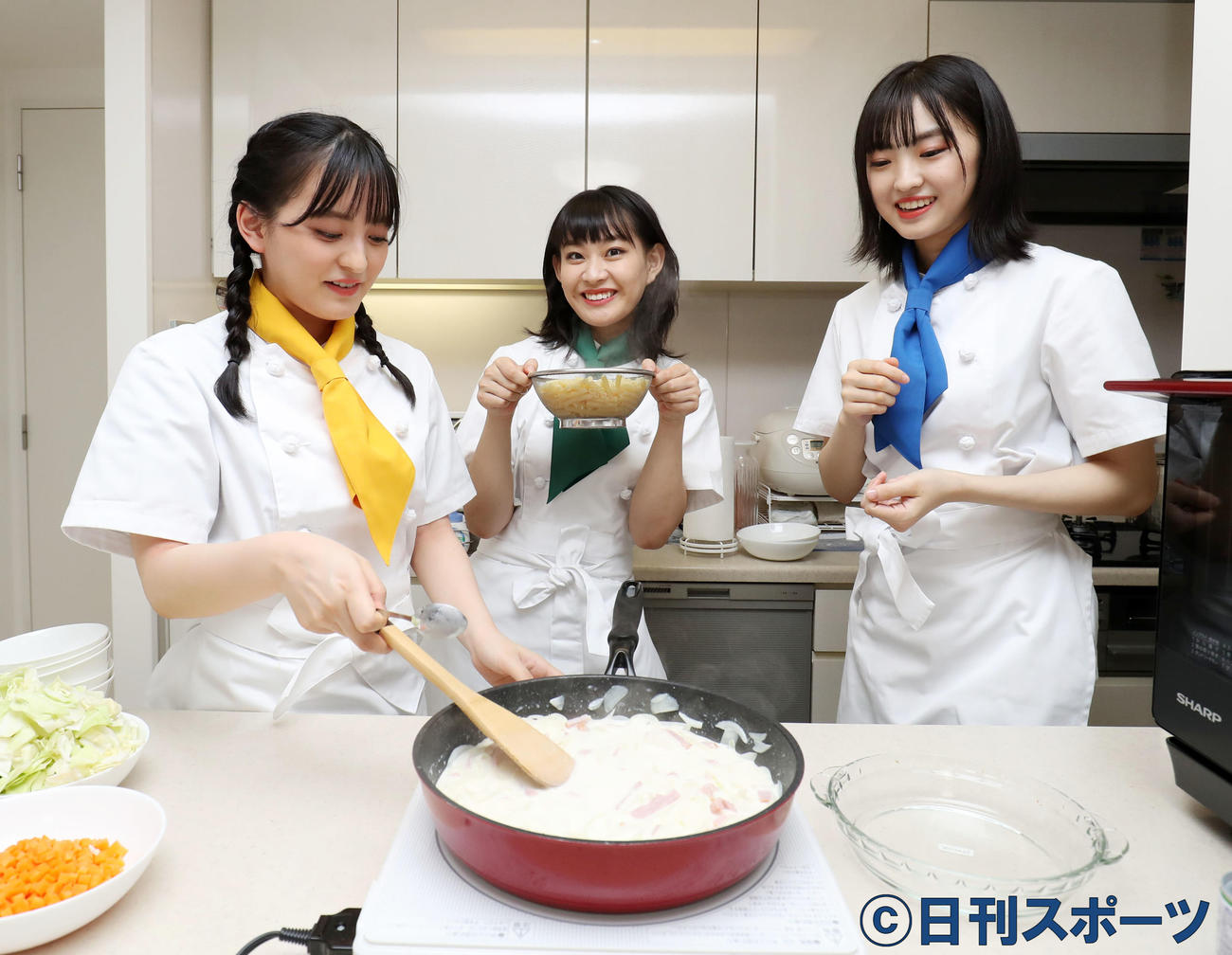 ゆであがったマカロニをクリームソースに入れる根岸（中央）、左は清井、右は春名