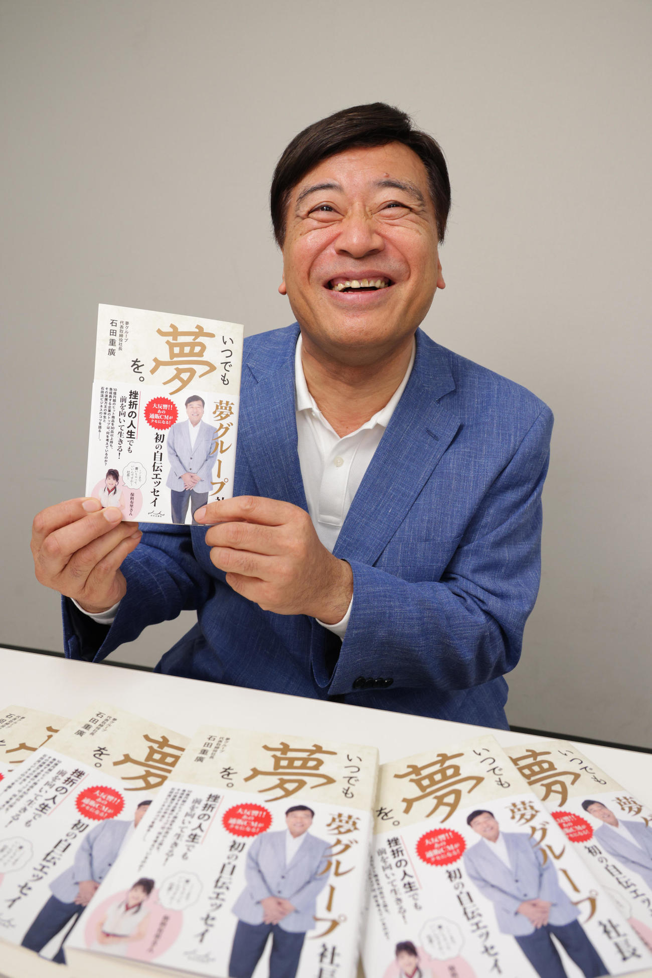 著書を手に笑顔を見せる夢グループ石田重廣社長（撮影・中島郁夫）