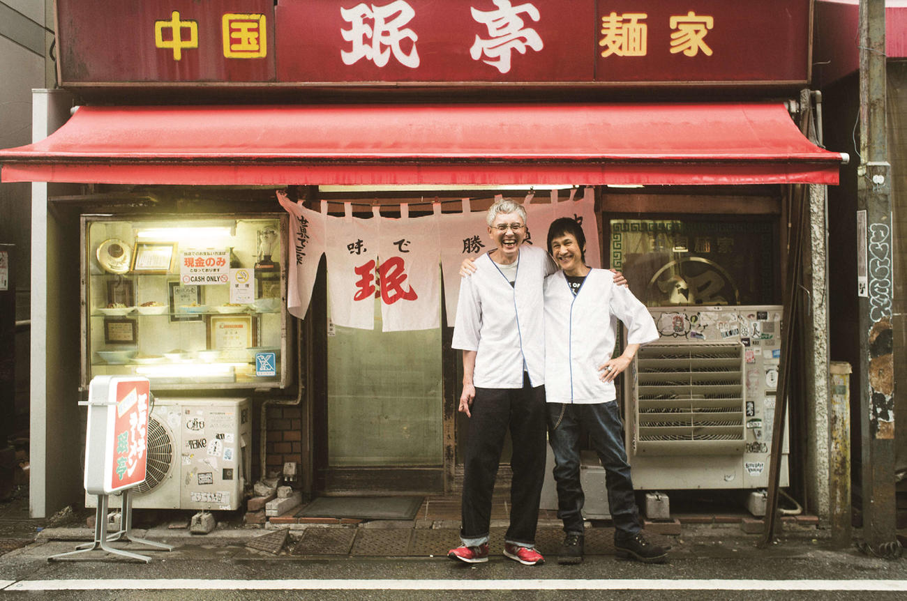 約40年前の同じ日にアルバイトを始めた東京・下北沢の中華料理屋「■亭」を前に、当時と同じアルバイト着に袖を通し、記念撮影した松重豊（左）と甲本ヒロト※■＝王ヘンに民