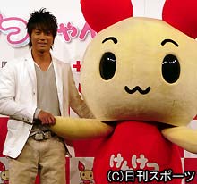 献血キャラクターの背中にそっと手を回し、エスコートする永井大