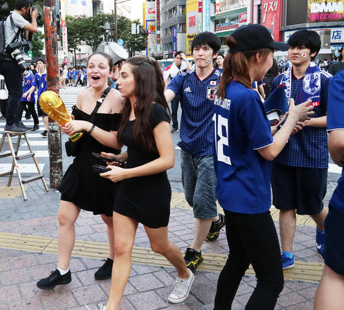 W杯トロフィーのレプリカを手に盛り上がる外国人の後方で悔しそうな表情を見せる日本人サポーター(撮影・足立雅史)