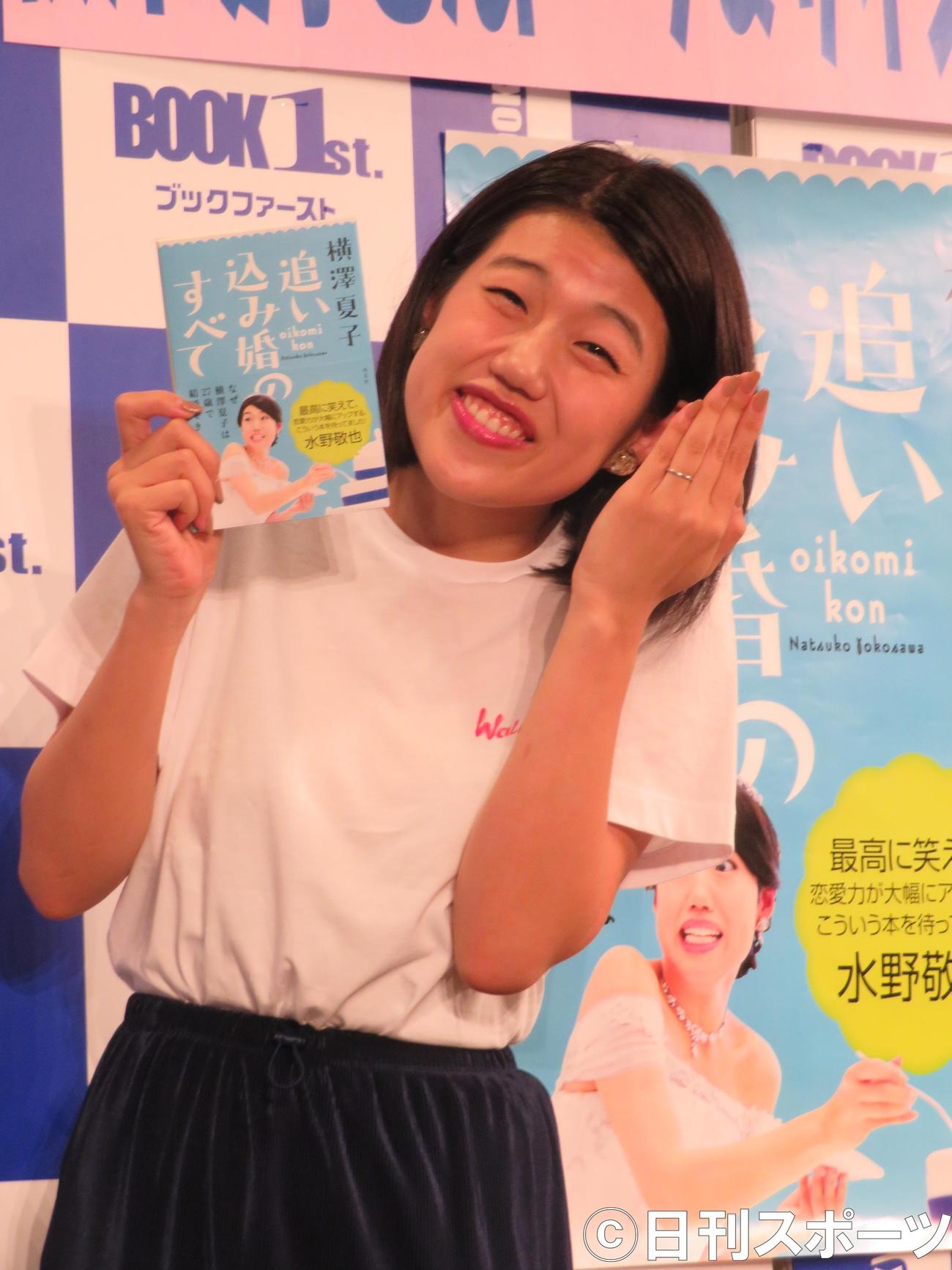 本と結婚指輪を披露し、満面の笑みを浮かべる横沢夏子