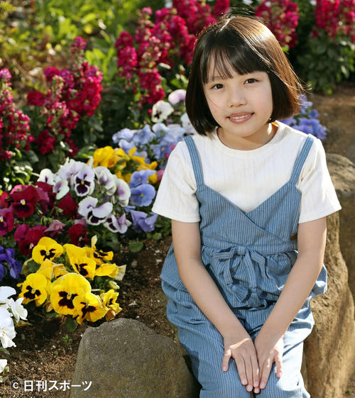 彩り豊かに咲いた花の横で笑顔を見せる粟野咲莉（撮影・松本俊）