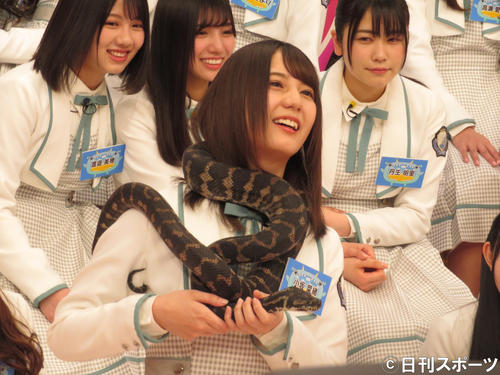 ヘビを首に巻いて笑顔を見せる小坂菜緒（撮影・横山慧）