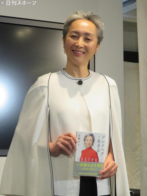 本を手にほほ笑む近藤サト