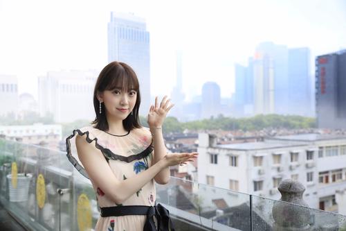 上海の街並みをバックに笑顔を見せる堀未央奈