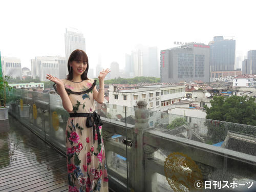 上海の街並みをバックに笑顔を見せる堀未央奈