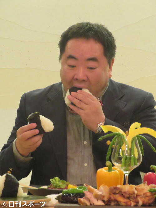 両手におにぎりを持ち、ほおばる塚地武雅