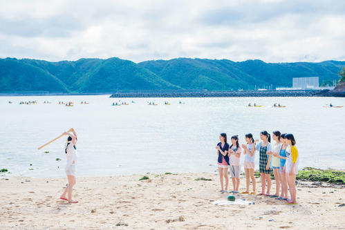 日向坂46初のグループ写真集のワンカット。沖縄の海辺でスイカ割りに挑戦