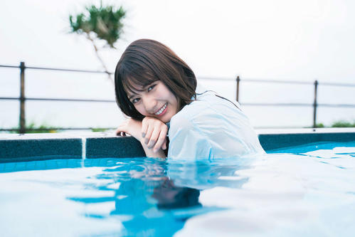 日向坂46初のグループ写真集のワンカット。プールで笑顔を見せる小坂菜緒
