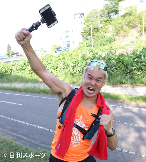 撮影機材のiPhone（アイフォーン）を片手に、猪木氏ばりの「ダァ～」で気合をみせる京谷氏（撮影・西塚祐司）