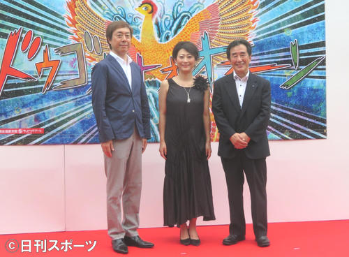 道後温泉本館ラッピングアートのウォールアートパネルの前に立つ友近（中央）。左はポニーキャニオン経営戦略本部の石川和雄副本部長、右は松山市の梅岡伸一郎副市長