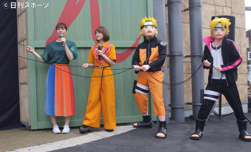 オープニングイベントで垂れ幕を引く左から足立梨花、生駒里奈、ナルト、ボルト